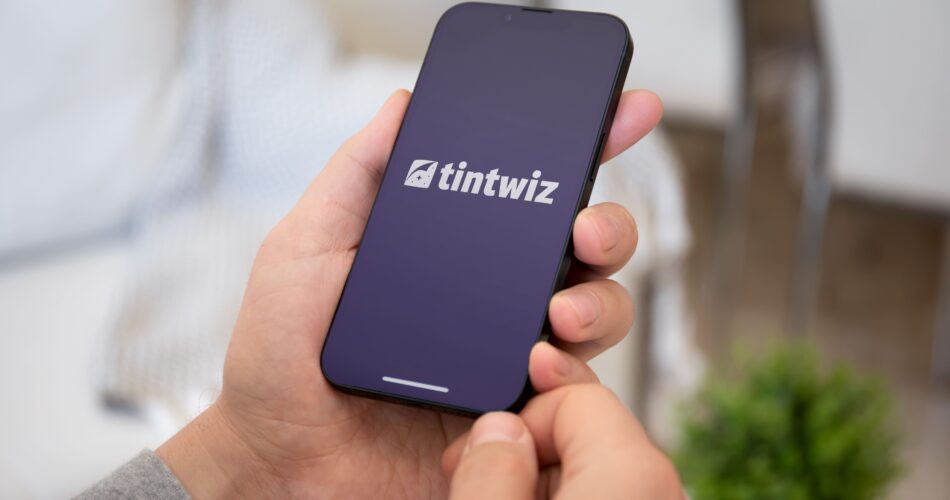 Hand holding iPhone with Tint Wiz logo on screen
